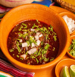 Lamb Birria con Consomé — slow-cooked lamb served in consomé
