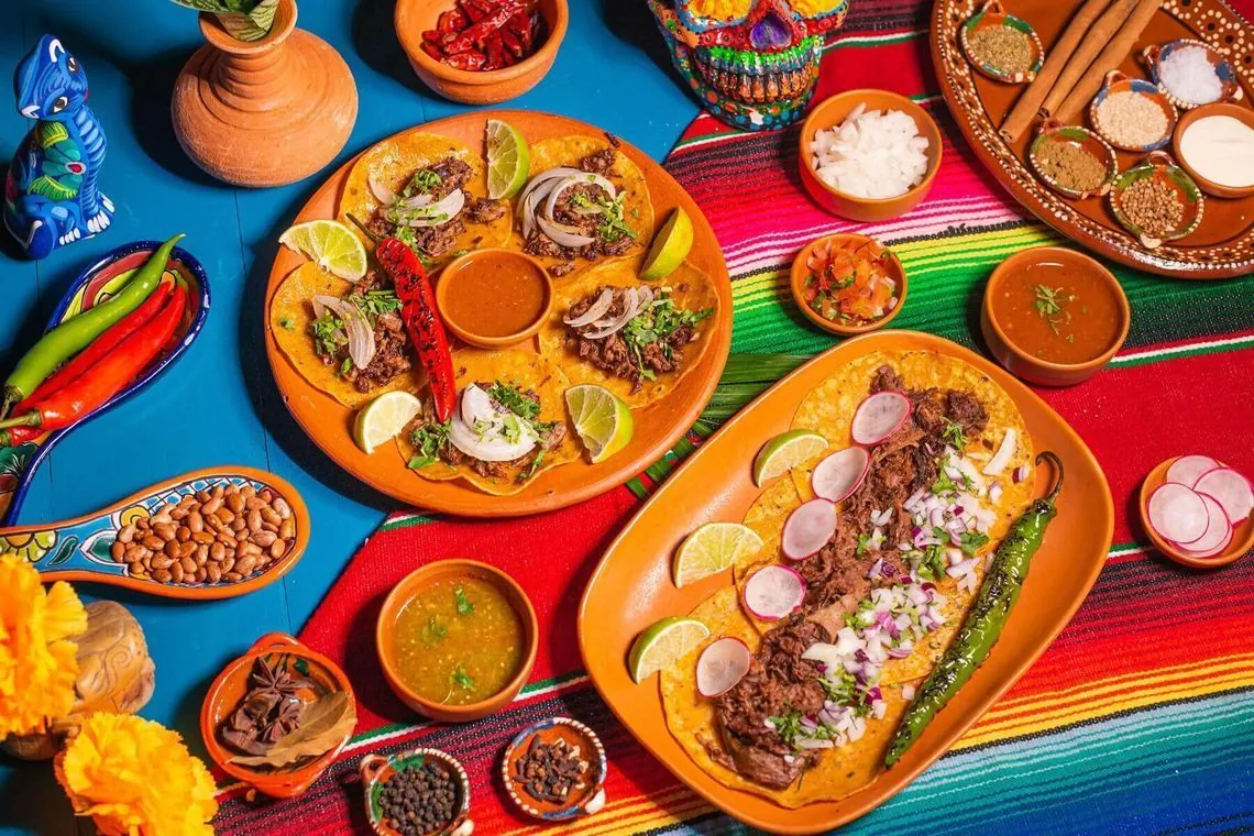 Tacos al Pastor and Lamb Birria platters on clayware at Danzante Bangkok